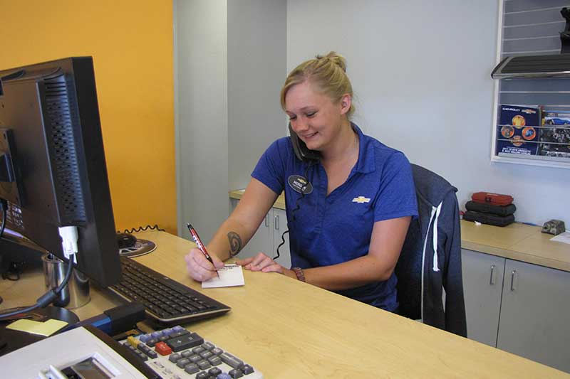 A woman at the Heritage Chevrolet -MI service center on a call with a customer